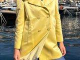 une femme vêtue d'un manteau jaune, debout au bord de l'eau