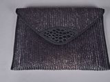 une image représentant un sac à main noir posé sur une surface blanche