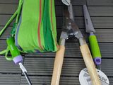 deux outils de jardinage et un sac vert posés par terre