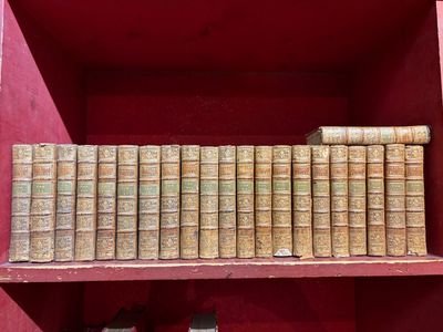de nombreux livres anciens sur une étagère rouge dans une pièce rouge