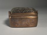 an old brass box with a design on it on a white surface