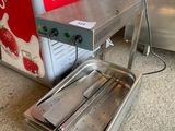 un réchauffeur de plats posé par terre à côté d'un distributeur de boissons gazeuses