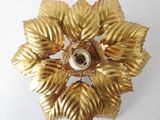 a gold flower with leaves on it on a white surface