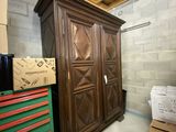 une armoire en bois au milieu d'une pièce, avec des cartons et encore des cartons par terre