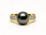 Gros plan sur une bague en perle noire et diamants posée sur une surface blanche