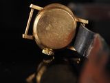 a close up of a gold watch on a black surface