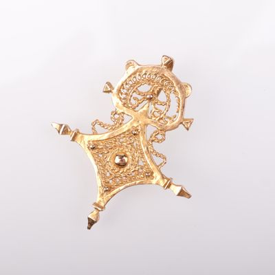 une image représentant une broche plaquée or sur laquelle figure une femme