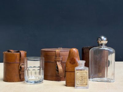several bottles and glasses on a table with leather cases