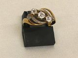gold and diamond ring on black stand on white cloth