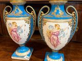 une paire de vases bleus et blancs posés sur une table, avec un tableau en arrière-plan