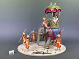 a figurine of an elephant with people riding on it