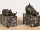 pair of bronze sculptures of rhinos on marble blocks on a table