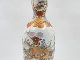 a white vase with a gold decoration on it