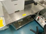 une imprimante posée sur un bureau en métal, à côté d'un ordinateur