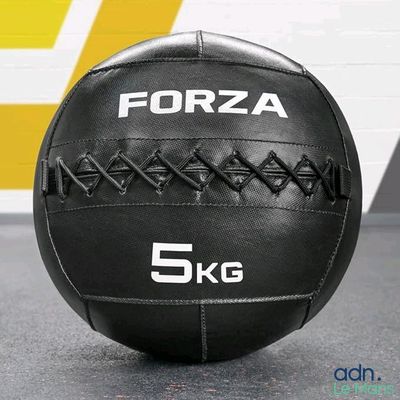 un ballon médicinal noir posé par terre dans une salle de sport