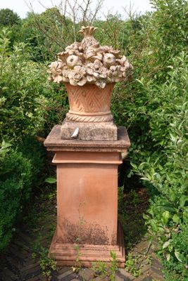 a large vase with flowers on top of it in the middle of a garden
