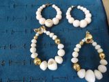 two pairs of white and gold beaded earrings on a blue cloth