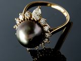 a close up of a black pearl and diamond ring on a black surface