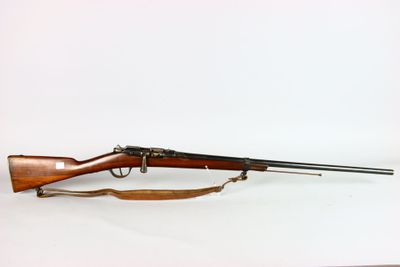 un vieux fusil posé sur une surface blanche, muni d'une crosse en bois