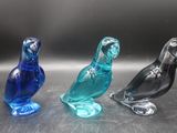 trois oiseaux en verre posés les uns à côté des autres sur une table