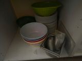 many bowls and pans on the shelf in the kitchen