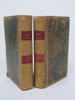 two old books sitting side by side on a white surface