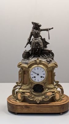 une horloge surmontée d'une statue, posée sur une table