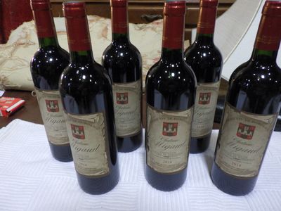 six bouteilles de vin rouge sont alignées sur une table