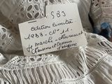 a white dress with a tag on it sitting on a bed