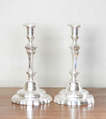 two silver candlesticks sitting on a wooden table