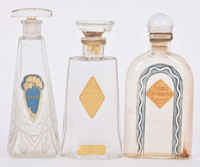 three bottles of perfume are lined up in a row on a white surface