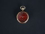 a close up of a pocket watch on a black surface