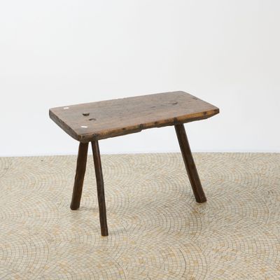 an old wooden bench sitting on top of a floor next to a white wall