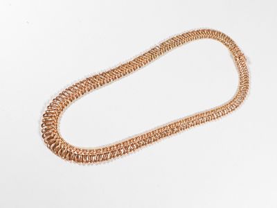 gros plan d'un collier en or sur une surface blanche