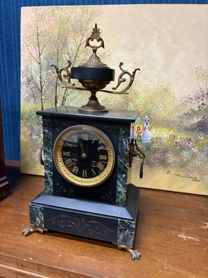 une horloge posée sur une table à côté d'un tableau