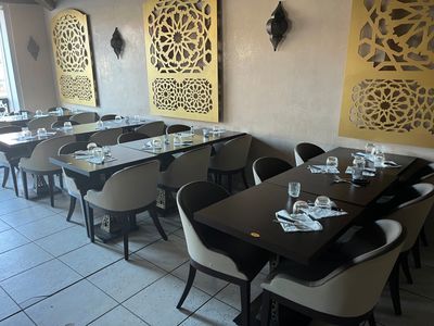 Il y a de nombreuses tables et chaises dans ce restaurant aux murs blancs et jaunes.