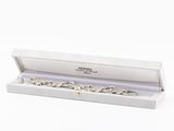 a close up of a silver bracelet in a box on a white background