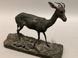 statue en bronze représentant un cerf posé sur un rocher, sur fond blanc