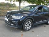 the black volkswagen suv is parked on the side of the road