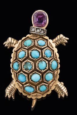 a close up of a turtle broochle with a purple stone in its shell