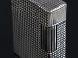 un gros plan d'un briquet argenté posé sur une surface noire