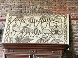 a cabinet with a painting on top of it in front of a brick wall