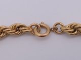 a close up of a gold bracelet on a white surface
