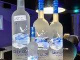 Trois bouteilles de vodka Grey Goose sont posées sur le comptoir d'un bar