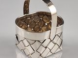 a silver basket with a handle on a white surface