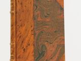 an old book with a marbled cover on a white surface