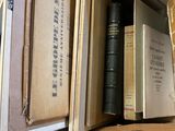 de nombreux livres dans une boîte posée sur une table, à côté d'un ordinateur portable