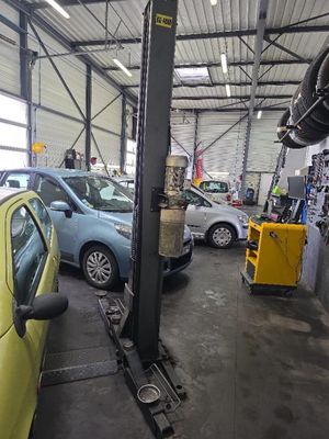 une voiture jaune garée dans un garage, avec d'autres voitures en arrière-plan