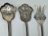 three silver spoons sitting on top of a white surface