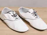 men ' s white dress shoes with black laces on a wooden table
